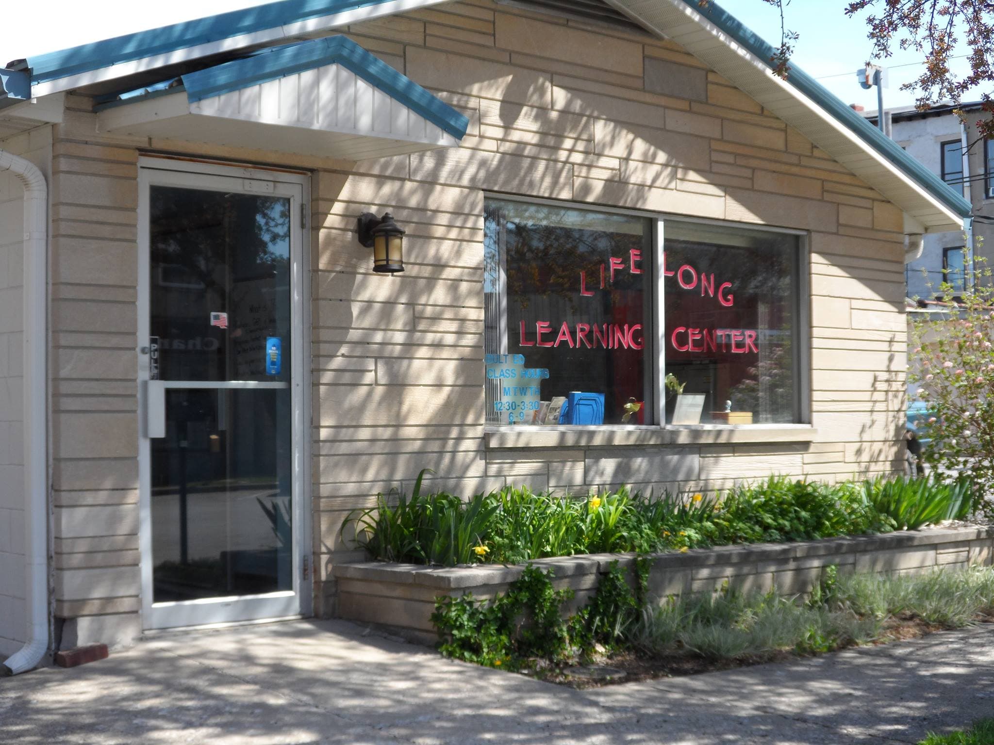 The exterior of the Lifelong Learning Center, a small building next to the Owen County Public Library, with "Lifelong Learning Center" painted on the front window.