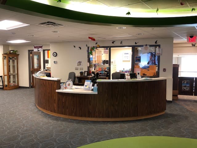 The Youth Services desk on the second floor of Owen County Public Library, with the librarian's chair, signage, and a view through the kids department windows.