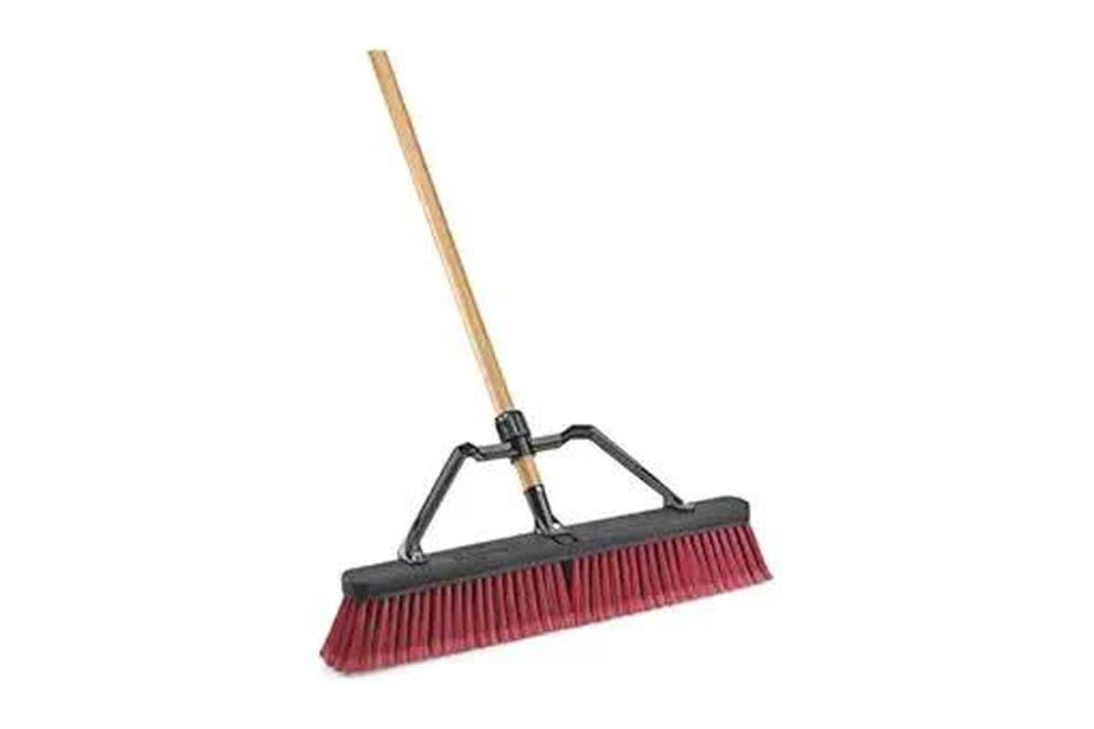 Push broom with a wooden handle and red and black bristles
